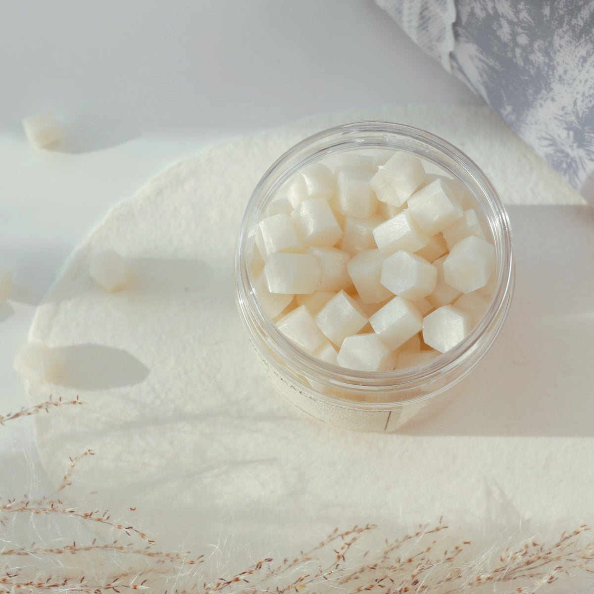 LimerenceSeals 'Lustr' handmade sealing wax beads in pure white, contained in a clear jar. The background features soft white textiles and dried plant decorations, creating a simple and fresh atmosphere. Perfect for letter sealing and craft projects.