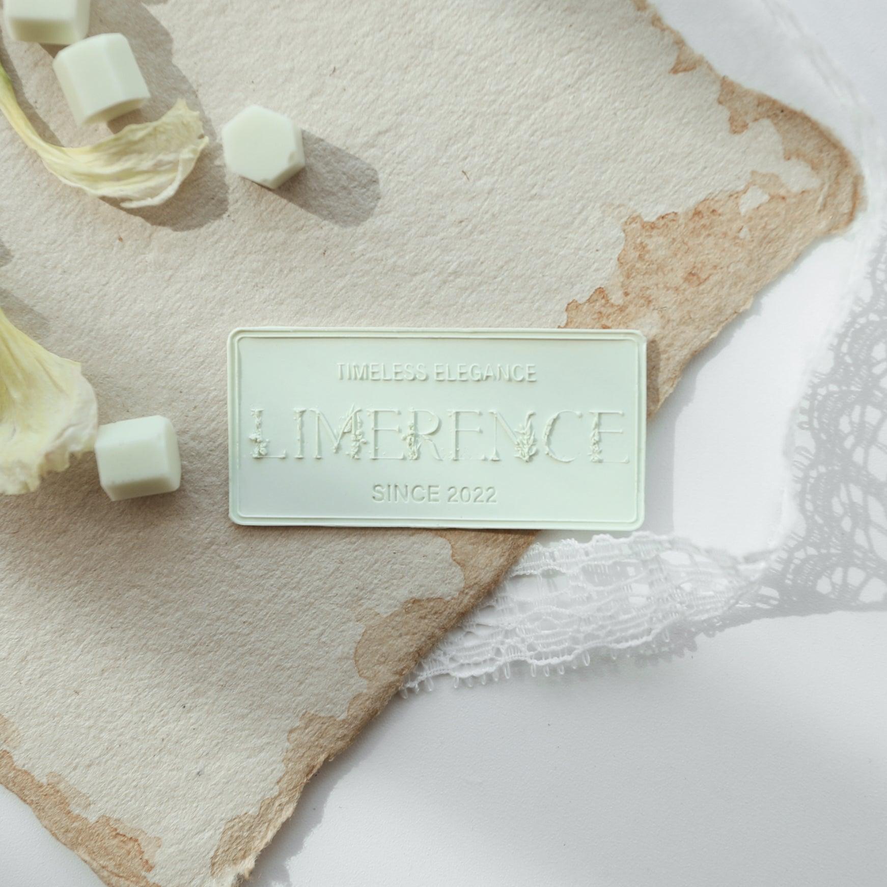 A mint green Limerence Seals label embossed with "TIMELESS ELEGANCE - LIMERENCE - SINCE 2022," placed on textured parchment paper. Surrounded by mint green Veloria handmade sealing wax beads and delicate lace, the setup exudes a sense of refined elegance and is perfect for enhancing invitations and sophisticated gift presentations.