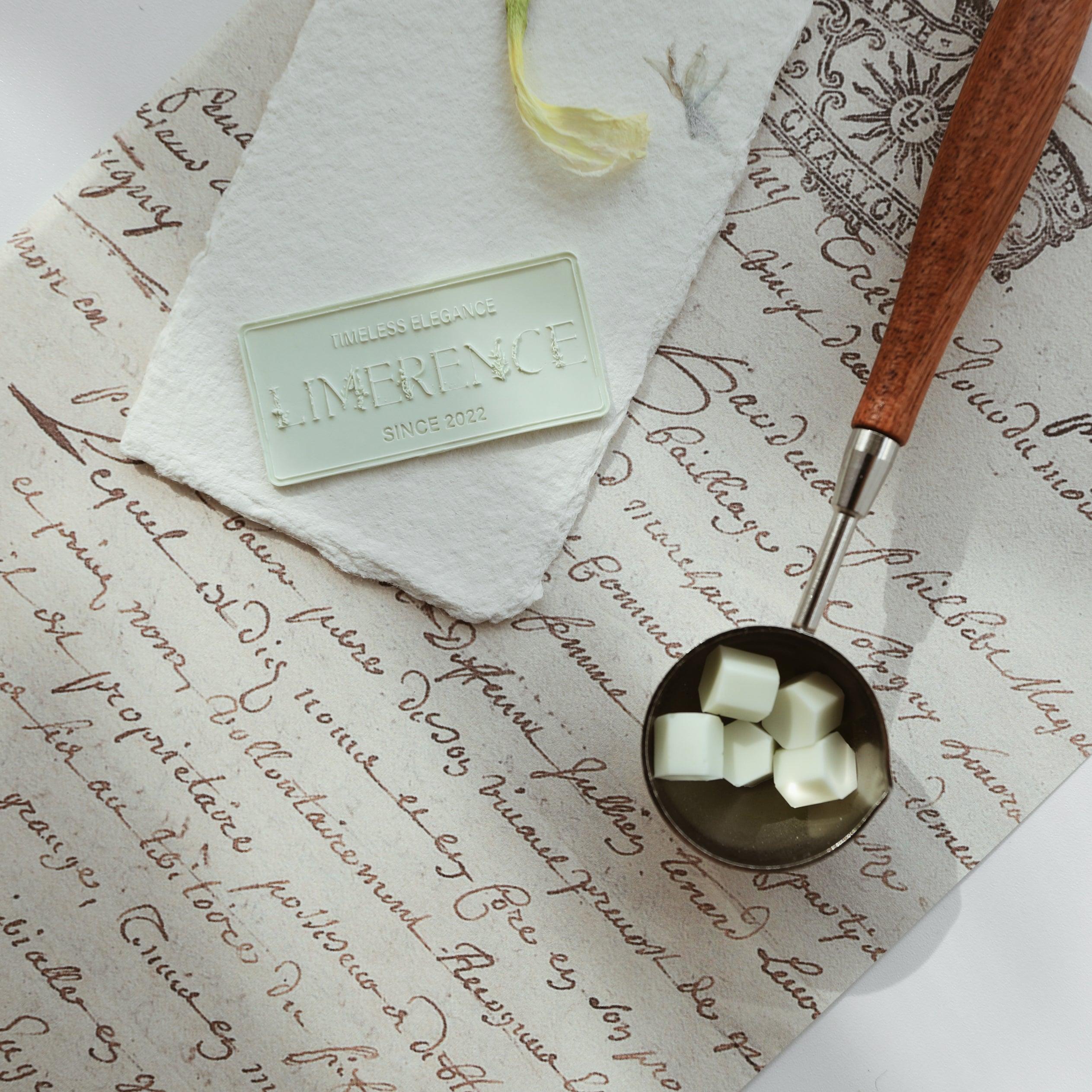 A mint green Limerence Seals label embossed with "TIMELESS ELEGANCE - LIMERENCE - SINCE 2022," placed on textured parchment with elegant script. Accompanied by a wooden-handled wax spoon filled with mint green Veloria handmade sealing wax beads, the setup showcases a blend of vintage charm and refined elegance, ideal for sophisticated letter sealing and gift presentations.