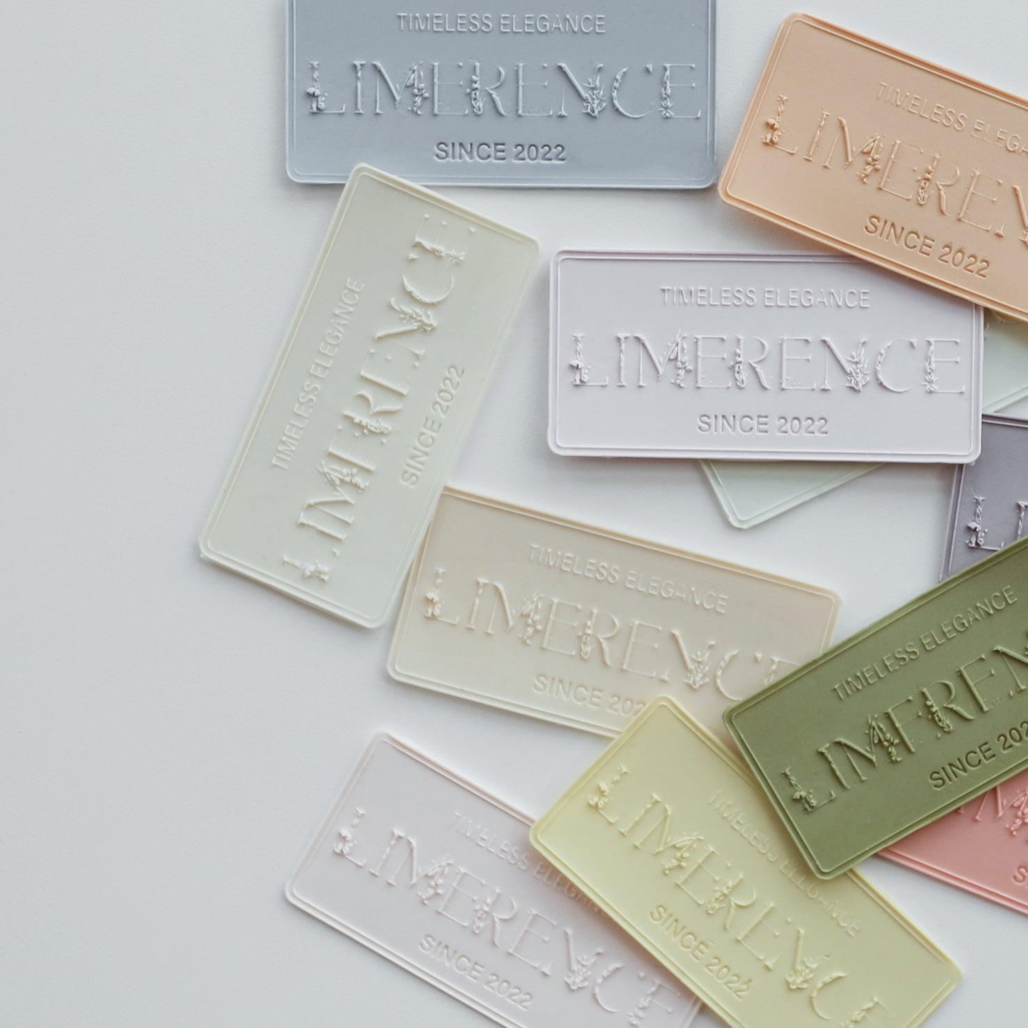 Collection of multicolored Limerence sealing wax samples, each embossed with "LIMERENCE - TIMELESS ELEGANCE SINCE 2022." The samples are arranged in a visually appealing layout, showcasing the variety of pastel colors available, such as light blue, peach, green, and cream, reflecting the brand's dedication to elegant and timeless designs.