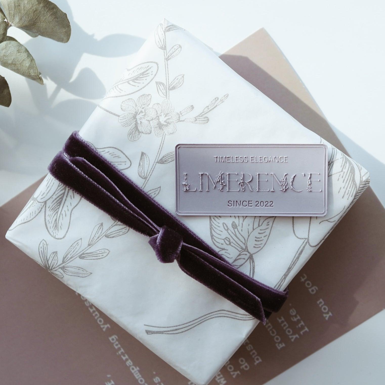 A beautifully wrapped gift adorned with a violet Limerence Seals label embossed with "TIMELESS ELEGANCE - LIMERENCE - SINCE 2022." The package features floral-patterned wrapping paper and a luxurious velvet ribbon, capturing a sense of sophistication and charm, perfect for elegant occasions and personalized gift presentations.